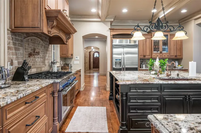 a kitchen with granite countertop a stove a sink and a refrigerator