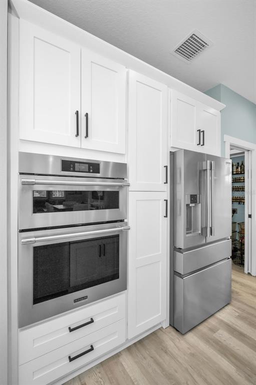 5650 Egrets Place New Port Richey, FL 34652 - Photo 22 of 73 a kitchen with white cabinets and stainless steel appliances