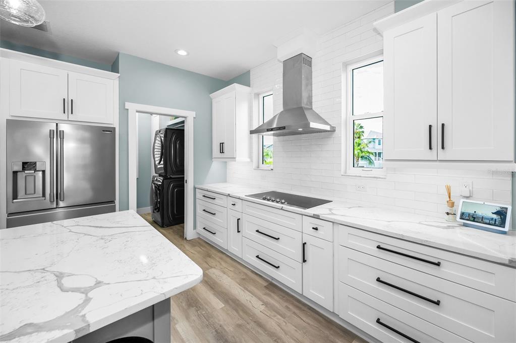 5650 Egrets Place New Port Richey, FL 34652 - Photo 23 of 73 a kitchen with stainless steel appliances kitchen island granite countertop a refrigerator a sink dishwasher a stove and white cabinets with wooden floor