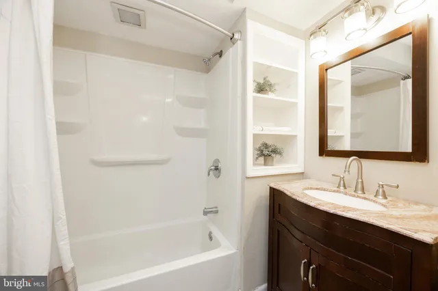 a bathroom with a bathtub shower sink and mirror