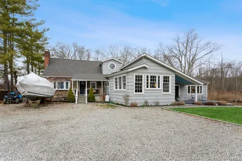 a front view of a house with a garden and trees