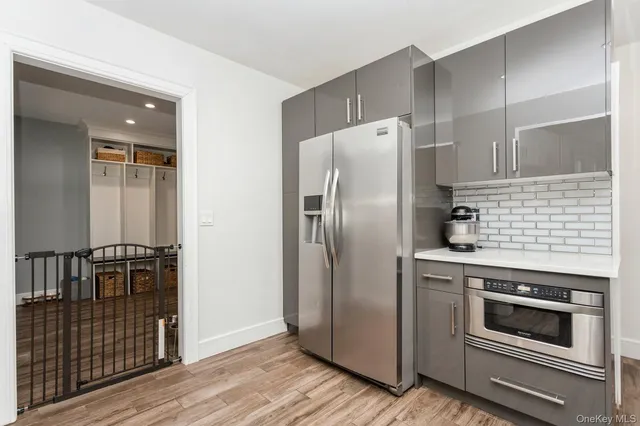 a kitchen with metallic refrigerator and wooden floor