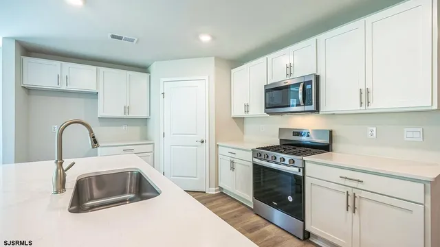 a kitchen with white cabinets a sink a stove and a refrigerator