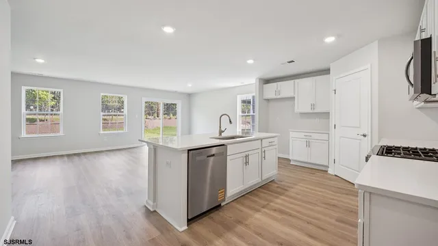 a kitchen with granite countertop a stove top oven sink and cabinets with wooden floor