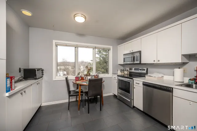 a kitchen with cabinets stainless steel appliances and a window