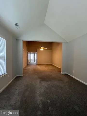an empty room with a chandelier fan and windows
