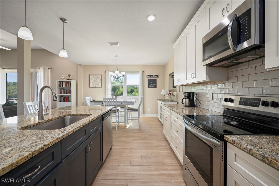 1606 Navigator Road Punta Gorda, FL 33983 - Photo 16 of 47 a large kitchen with stainless steel appliances granite countertop a lot of counter space a sink and dishwasher a stove top oven with wooden floor
