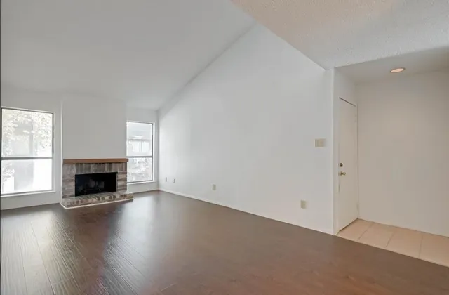 an empty room with floor to ceiling window and fireplace