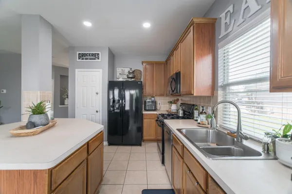a kitchen with kitchen island granite countertop a sink a counter top space appliances and cabinets