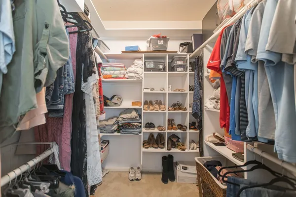 a view of walk in closet with clothes and shoes