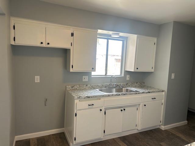 a bathroom with a granite countertop white cabinets and a sink