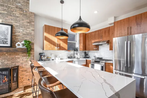 a kitchen with stainless steel appliances a stove a refrigerator and a fireplace