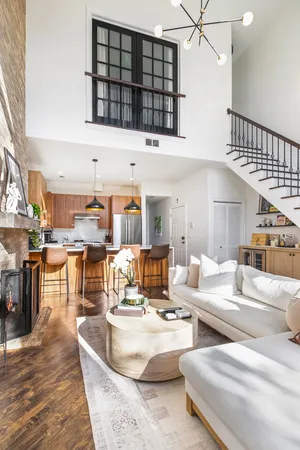 a living room with couches and kitchen view with wooden floor