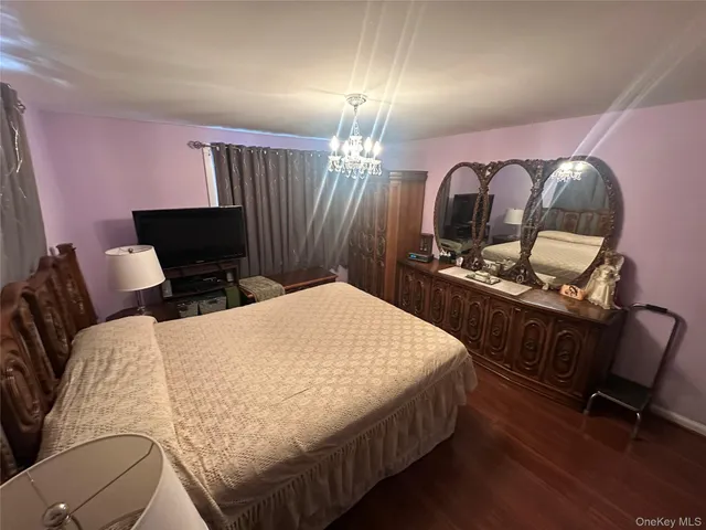 a bedroom with a bed and a flat tv screen on dresser