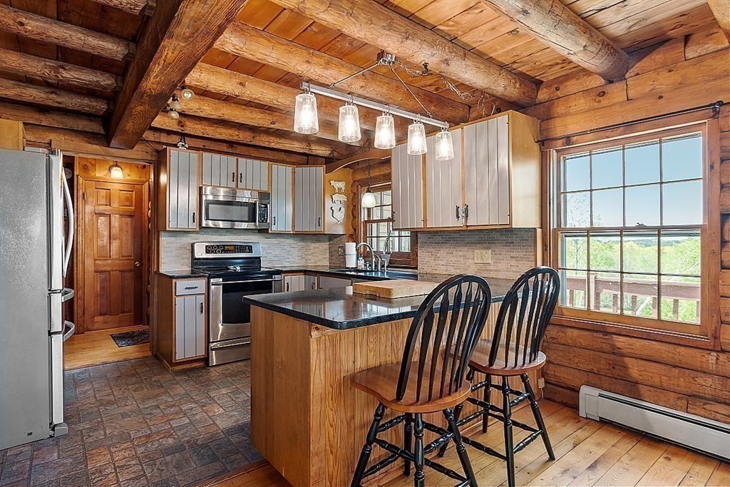 115 Gray Road Templeton, MA 01468 - Photo 17 of 40 a kitchen with stainless steel appliances granite countertop a stove a refrigerator a sink a dining table and chairs with wooden floor