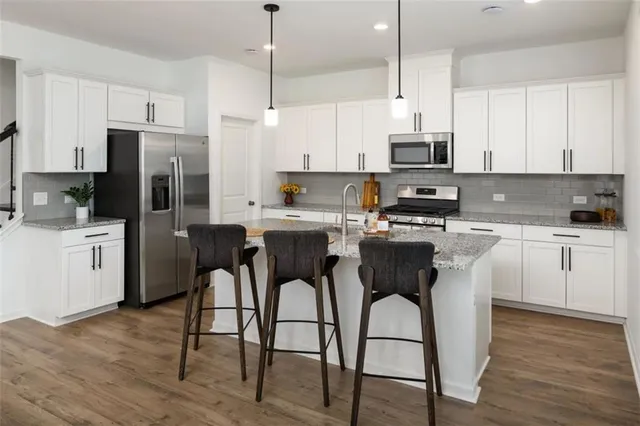 a kitchen with stainless steel appliances a stove a sink refrigerator and white cabinets with wooden floor