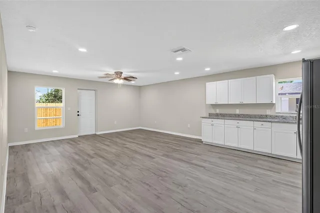 a view of an empty room with window and wooden floor
