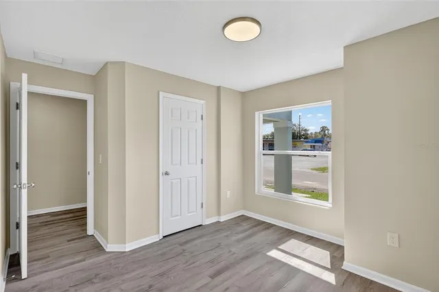 an empty room with wooden floor closet and windows