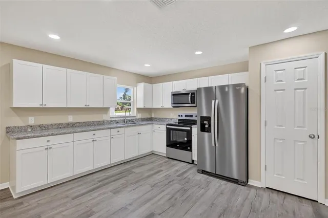 a kitchen with granite countertop cabinets stainless steel appliances a sink and a window