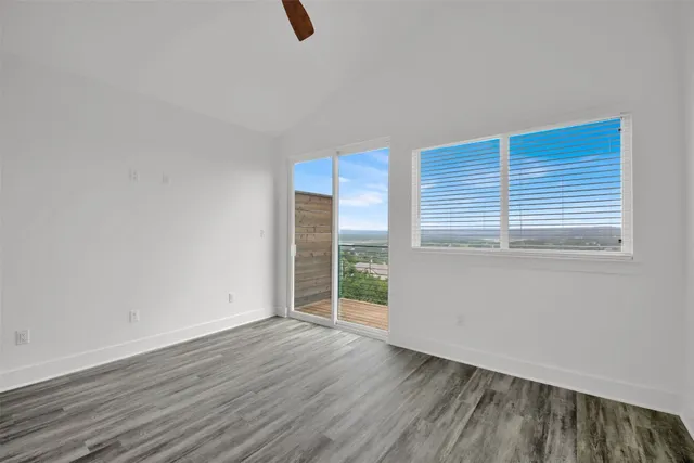 a view of an empty room with wooden floor and a bathroom