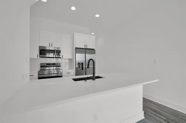 a kitchen with stainless steel appliances a sink a stove and a refrigerator with wooden floor