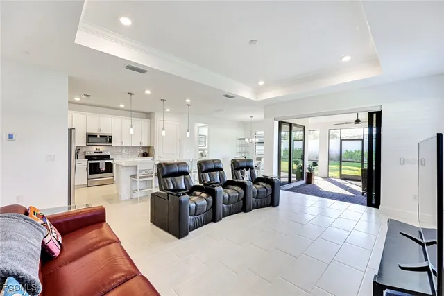 a living room with furniture kitchen area and a large window