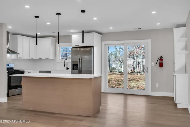 a large kitchen with stainless steel appliances granite countertop a stove a sink and a refrigerator