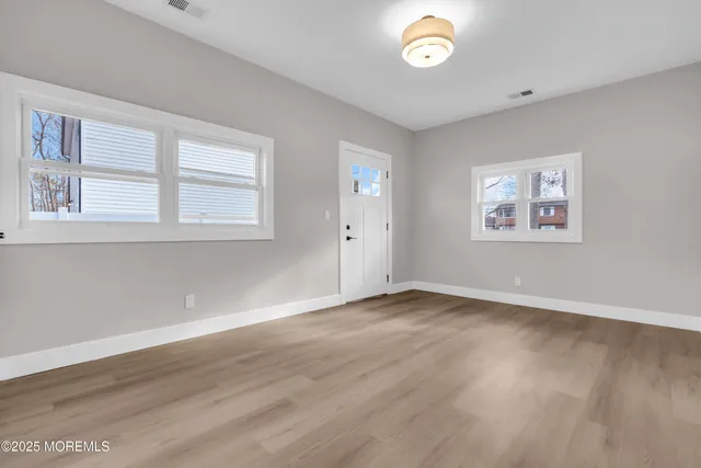 a view of an empty room with a window and wooden floor