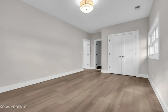 a view of an empty room with wooden floor and entryway
