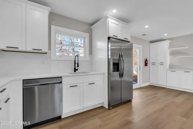 a kitchen with a refrigerator a sink and wooden floor