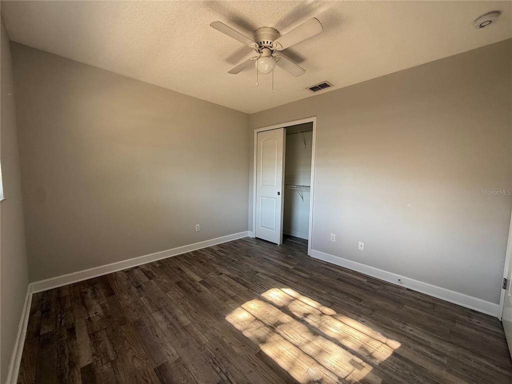 5839 12th Street Zephyrhills, FL 33542 - Photo 13 of 20 an empty room with wooden floor and fan