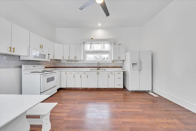a kitchen with granite countertop white cabinets and white appliances