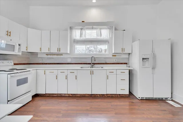 a kitchen with granite countertop white cabinets and white appliances