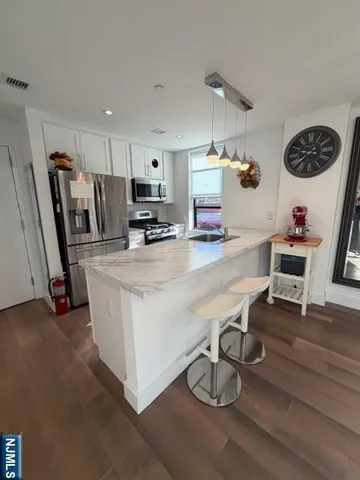 a kitchen with granite countertop a stove a sink and a wooden floor