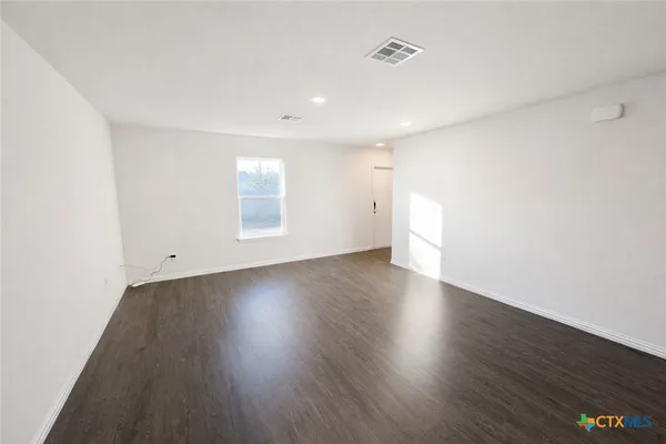 an empty room with wooden floor and window