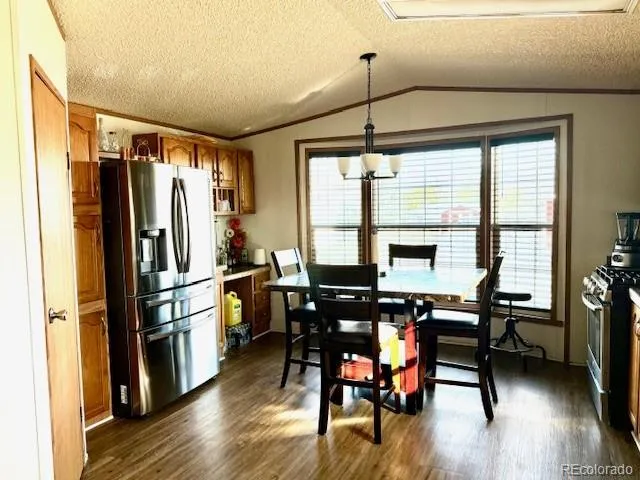 a kitchen with stainless steel appliances a dining table chairs refrigerator and wooden floor