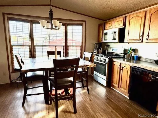 a kitchen with stainless steel appliances granite countertop a stove a sink dishwasher a dining table and chairs with wooden floor