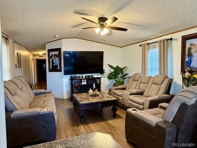 a living room with furniture a ceiling fan and a flat screen tv