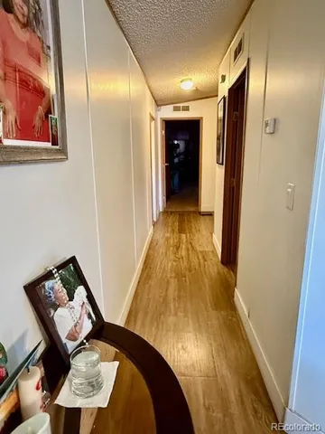 a view of a hallway with wooden floor and bathroom