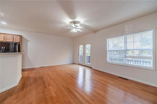 a view of an empty room with a window and wooden floor