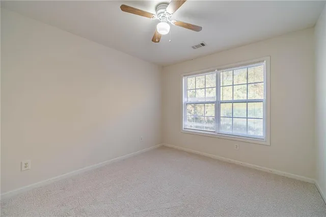 an empty room with a window and a fan