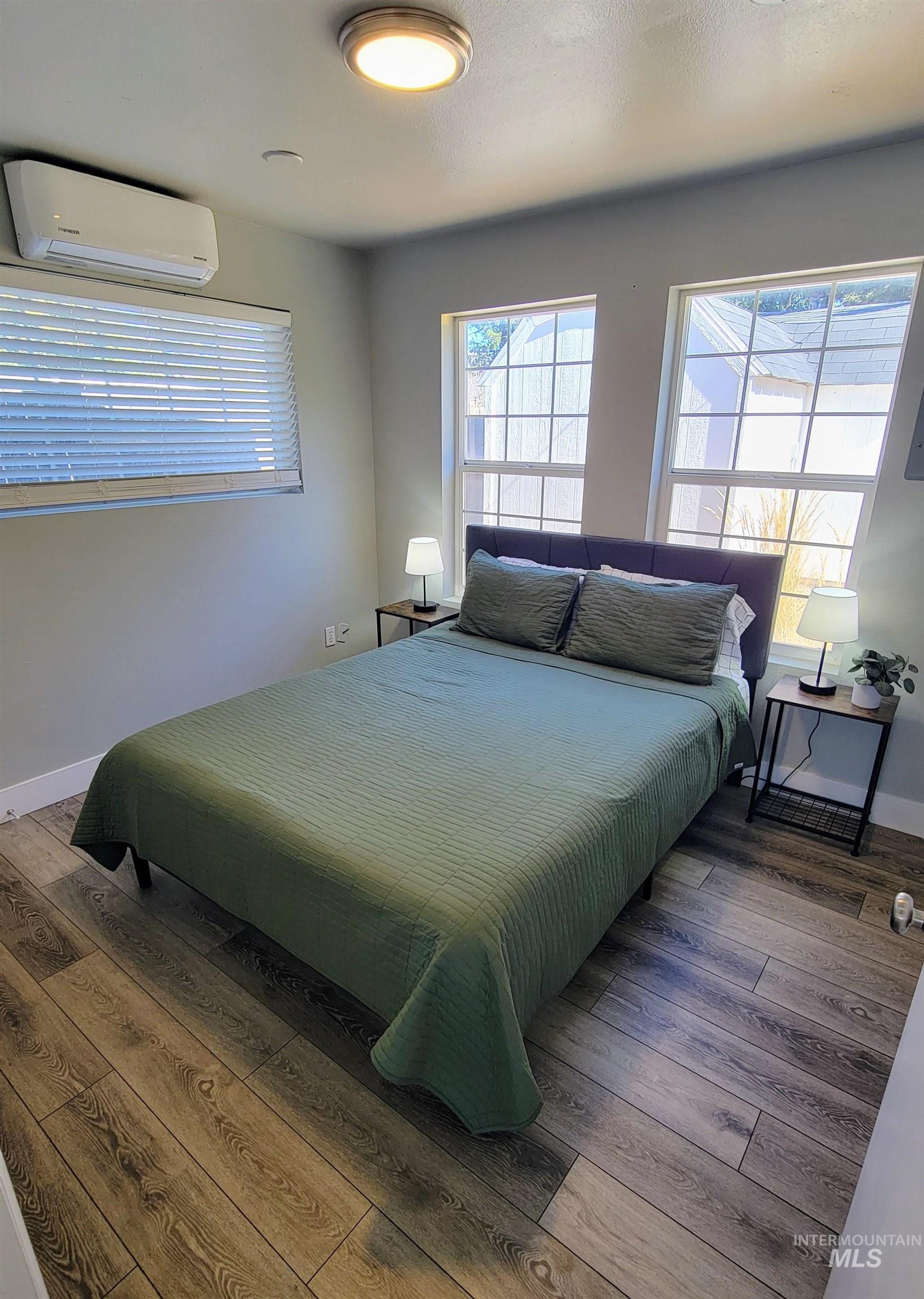 814 Baker Street Boise, ID 83706 - Photo 21 of 26 Room featuring wood-finish flooring, multiple windows with blinds, a ceiling-mounted light fixture, and a wall-mounted mini-split HVAC unit