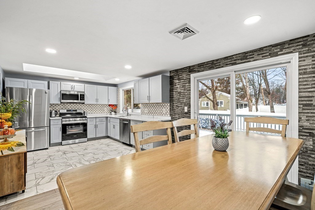 28 Sycamore Road Methuen, MA 01844 - Photo 7 of 35 a kitchen with stainless steel appliances kitchen island granite countertop a stove top oven a sink a dining table and chairs with wooden floor