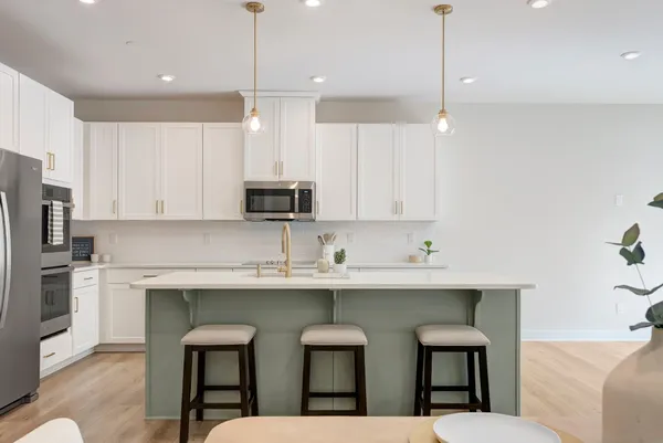 a kitchen with stainless steel appliances granite countertop a sink a stove a refrigerator and island with wooden floor