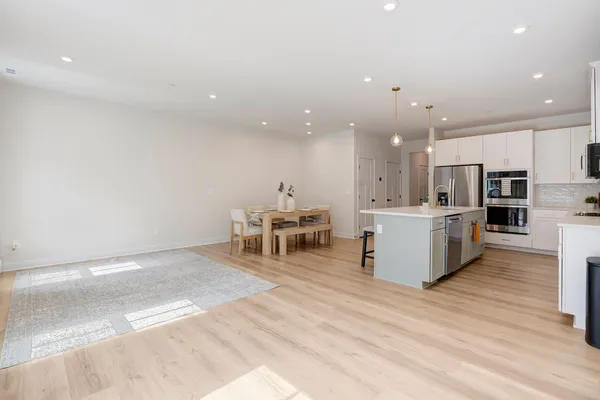 a large white kitchen with kitchen island a sink a stove and a refrigerator with wooden floor