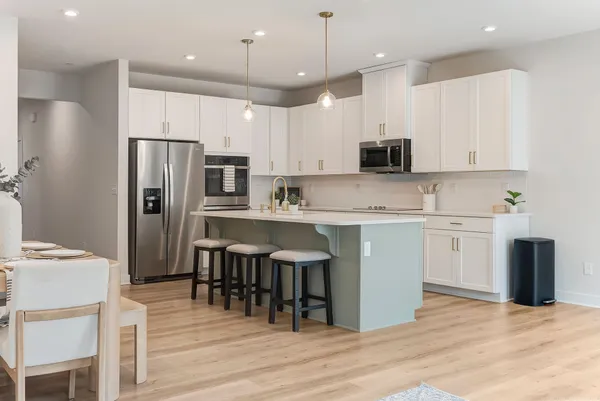 a kitchen with stainless steel appliances granite countertop a refrigerator a stove a microwave oven a sink dishwasher and white cabinets with wooden floor