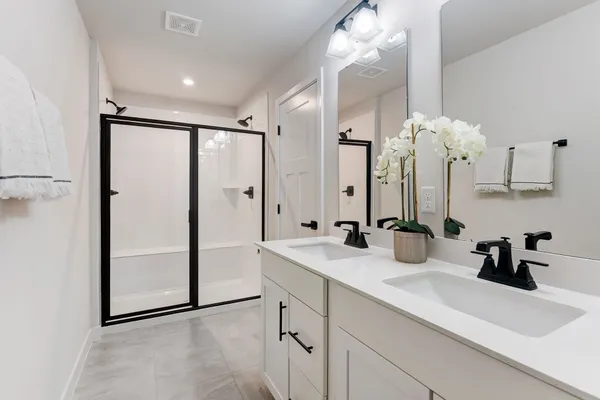a bathroom with a double vanity sink mirror and shower