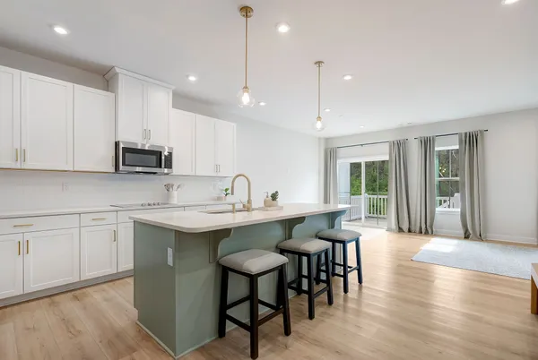 a kitchen with stainless steel appliances granite countertop a stove a sink a microwave a island with a dining table and chairs
