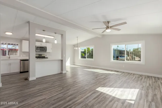 a view of an empty room with window and wooden floor