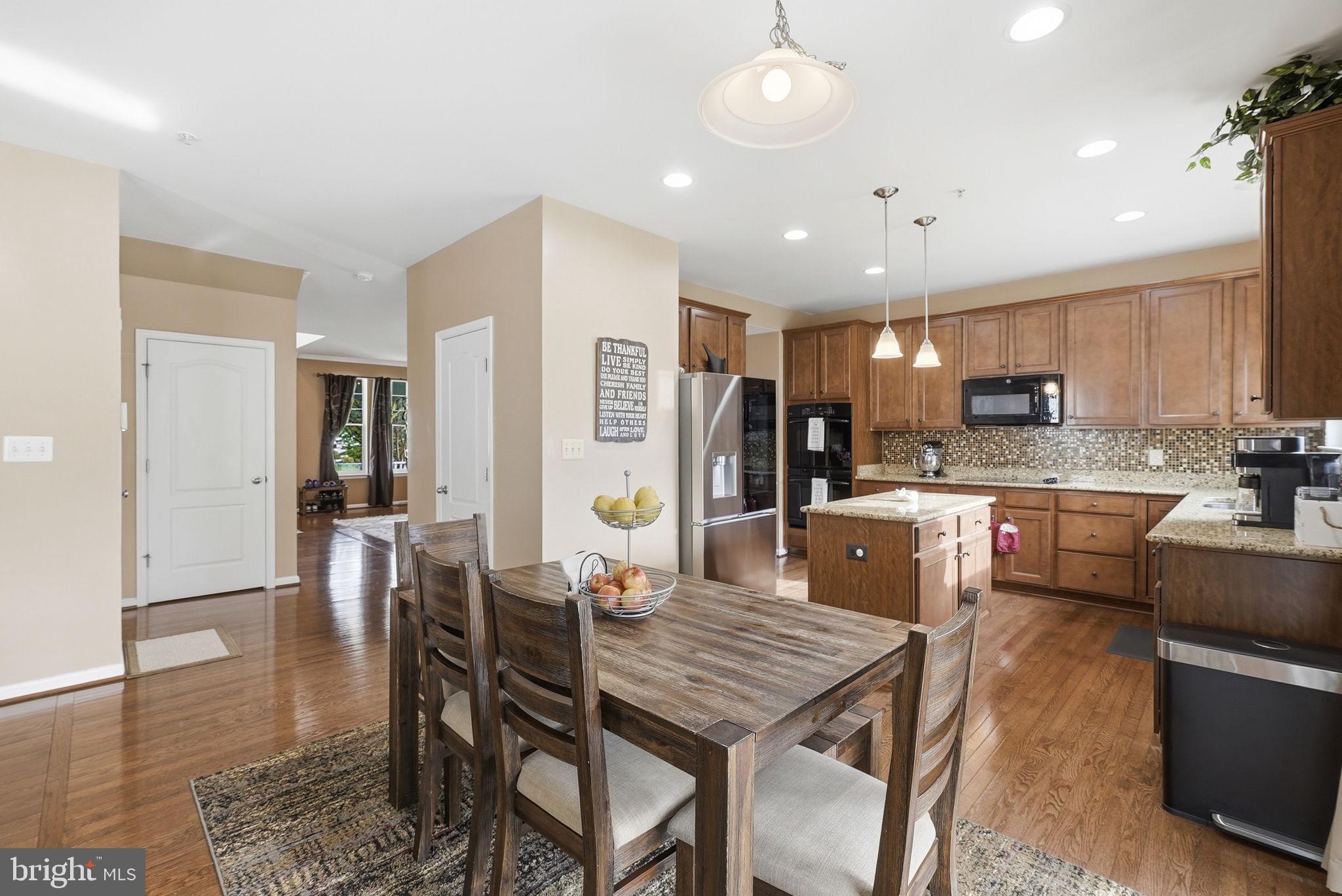 6900 Lenape Court Brandywine, MD 20613 - Photo 9 of 43 a kitchen with stainless steel appliances kitchen island granite countertop a refrigerator a stove a sink a dining table and chairs